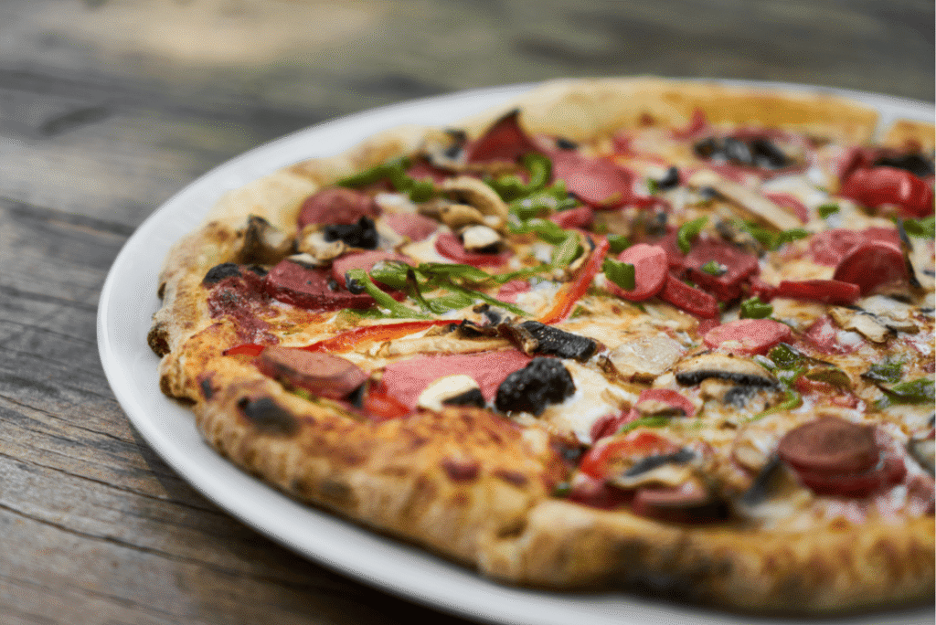 Pizza with olives, peppers, mushroom on a plate close out