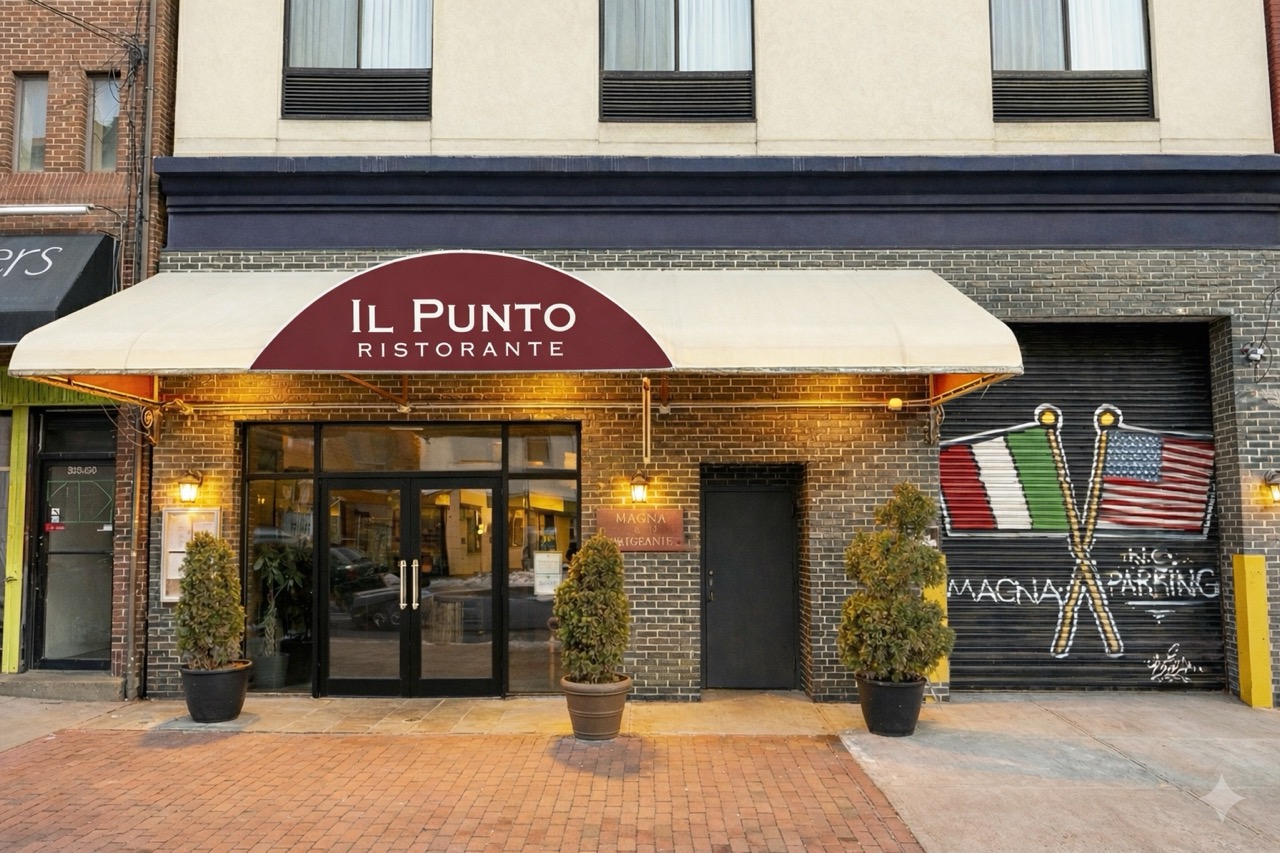 View of the main entrance of Il Punto Flushing white honing with the logo on top glass doors
